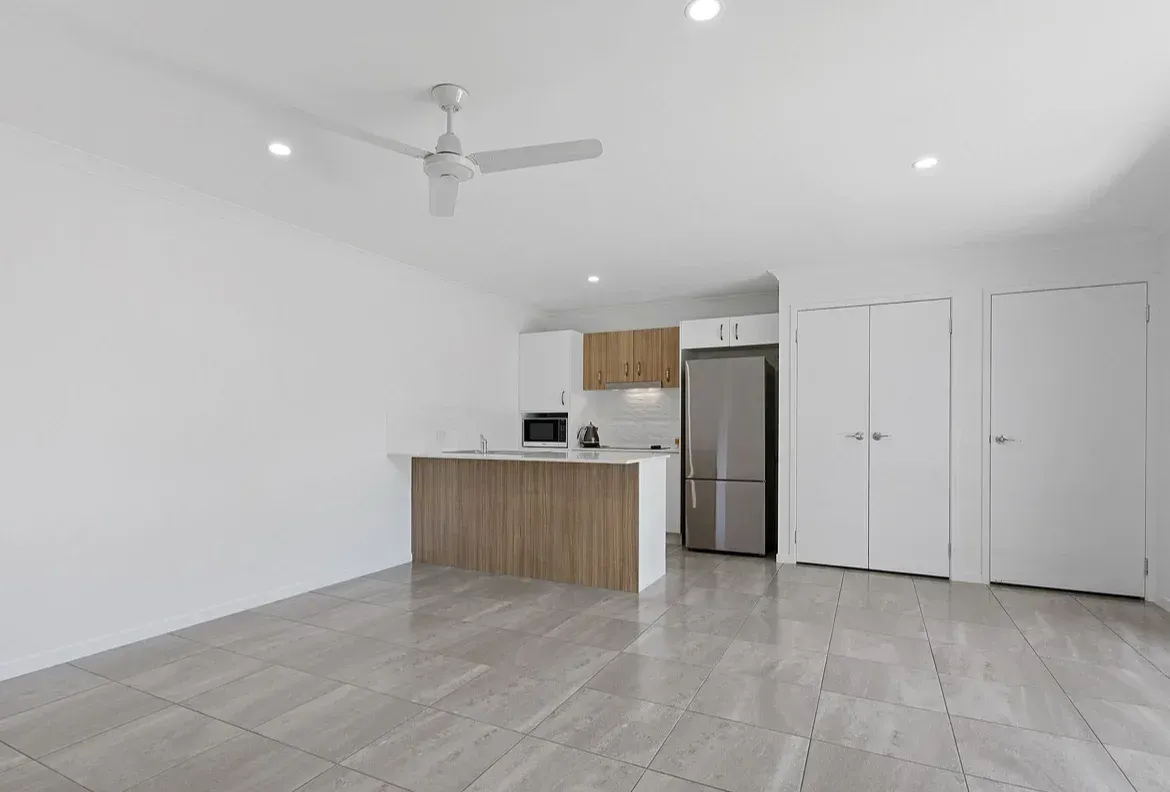 An Empty Living Room With a Ceiling Fan and a Kitchen — O'Brien Painting Contractors in Alexandra Headland, QLD