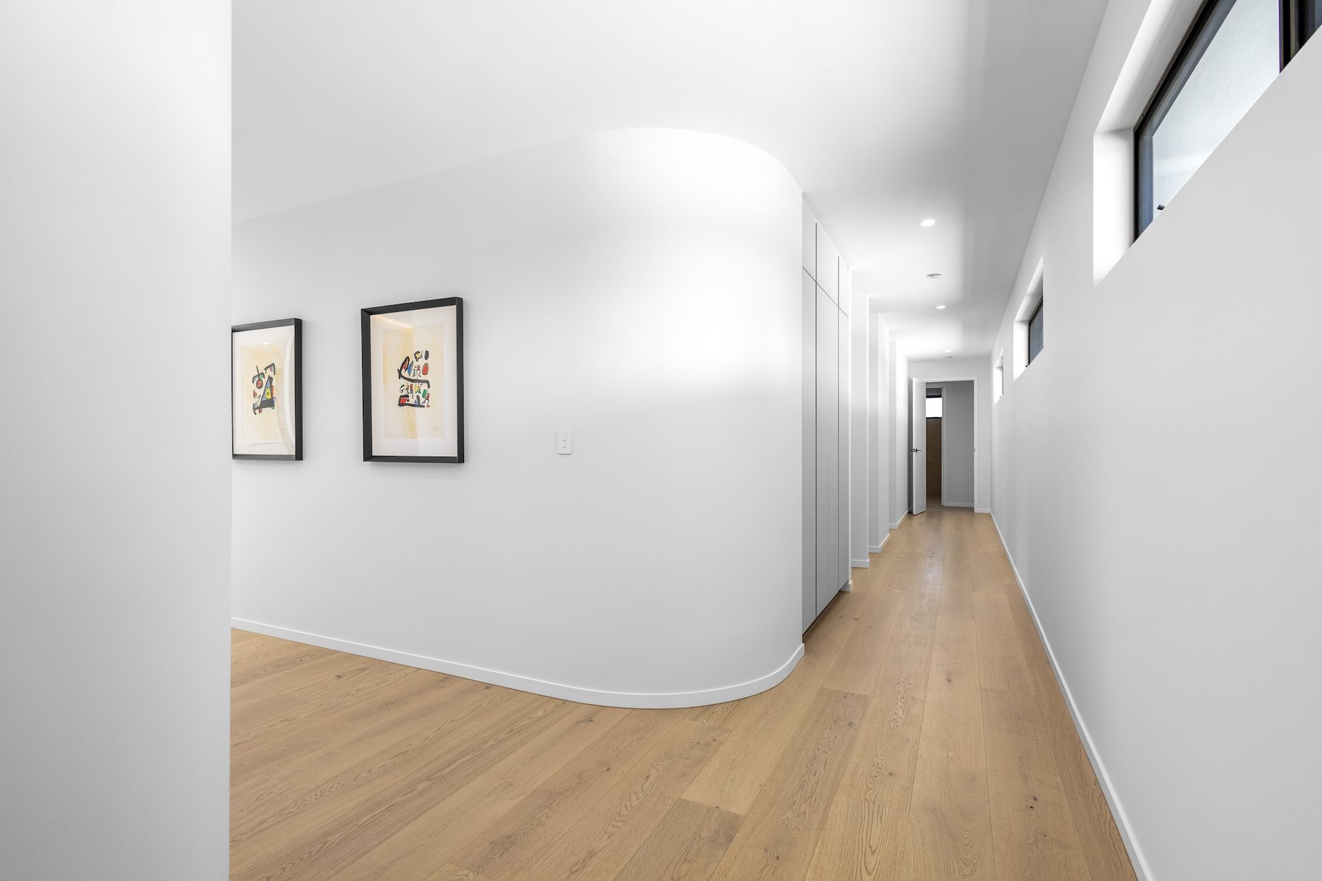 Long hallway with white walls and wooden floor. Two framed prints hang on one wall — O'Brien Painting Contractors in Alexandra Headland, QLD 