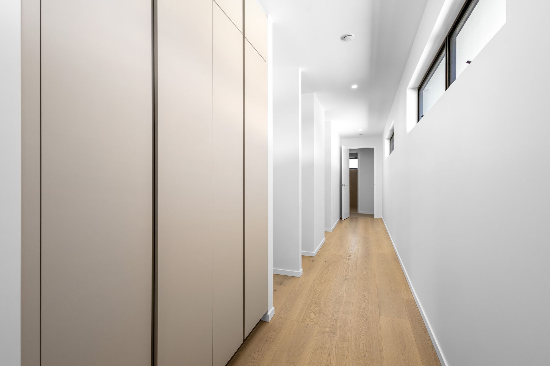 Long, narrow hallway with light wood floor, white walls, and built-in closet — O'Brien Painting Contractors in Alexandra Headland, QLD
