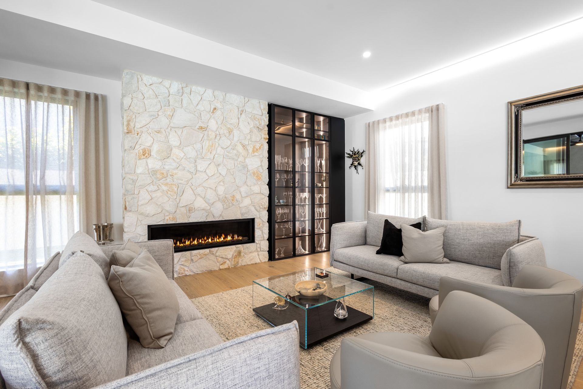 Living room with stone fireplace, glass cabinet, two couches, and neutral decor— O'Brien Painting Contractors in Alexandra Headland, QLD