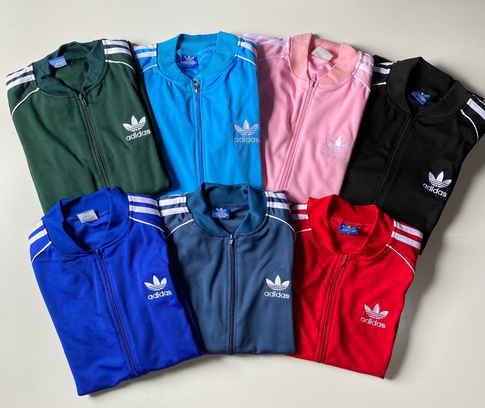 Siete chaquetas deportivas Adidas de varios colores (verde, azul, rosa, negro, azul marino y rojo).