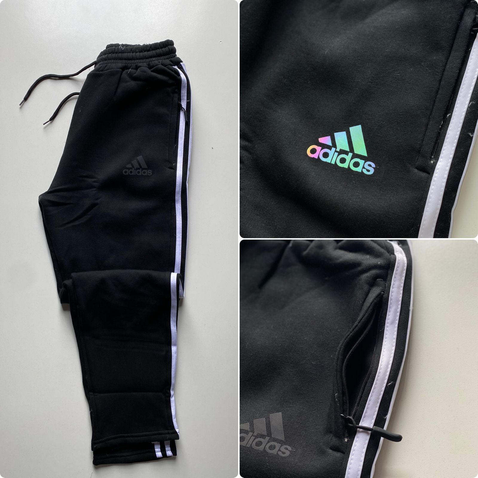 Pantalones deportivos negros de Adidas con rayas laterales, bolsillos con cremallera y un logotipo iridiscente .
