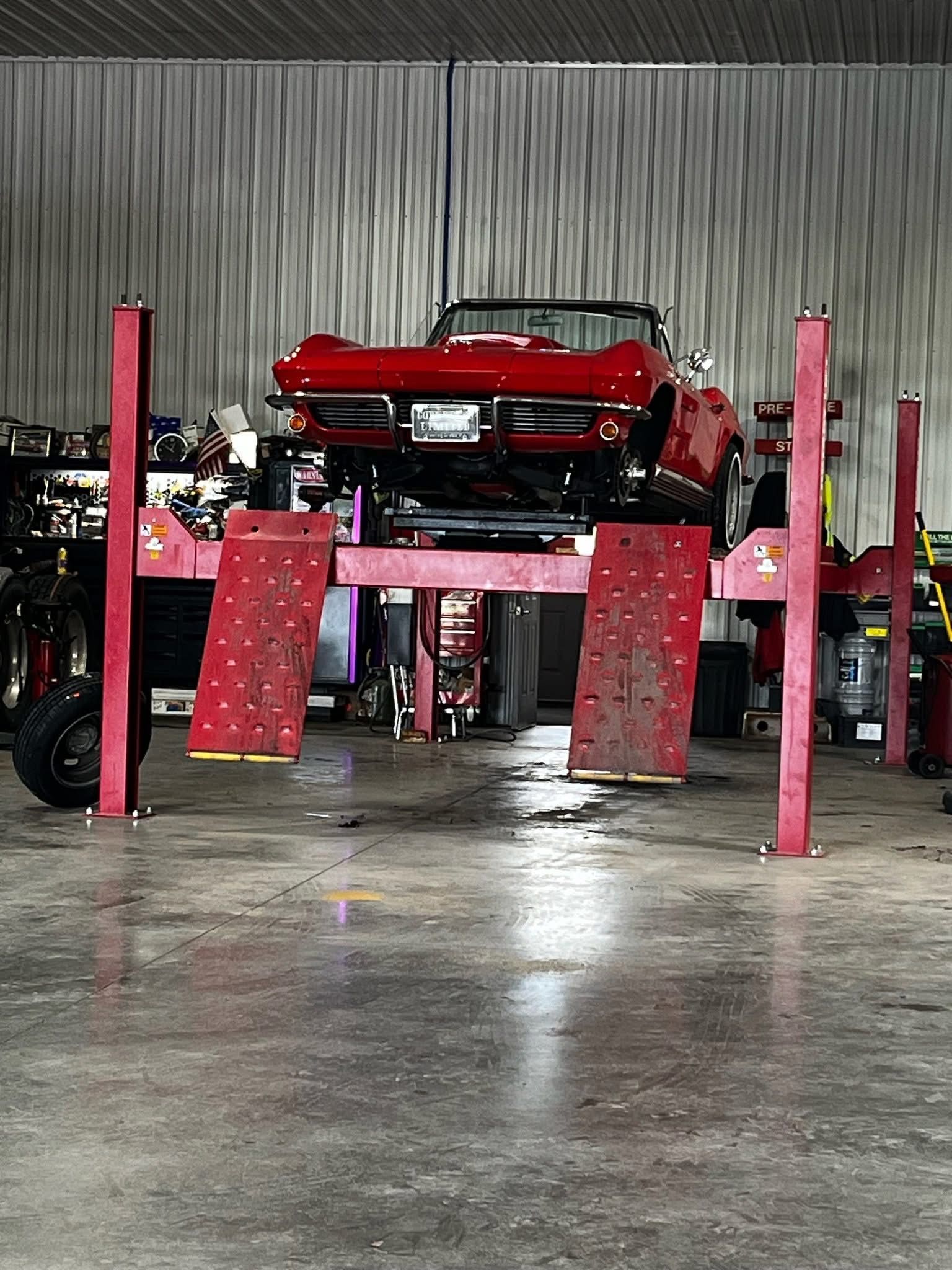 Green car on a flatbed tow truck traveling on a highway, with green foliage in the background.