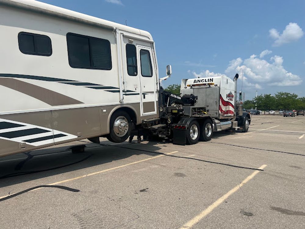 Motorhome attached to a semi-truck in a parking lot.