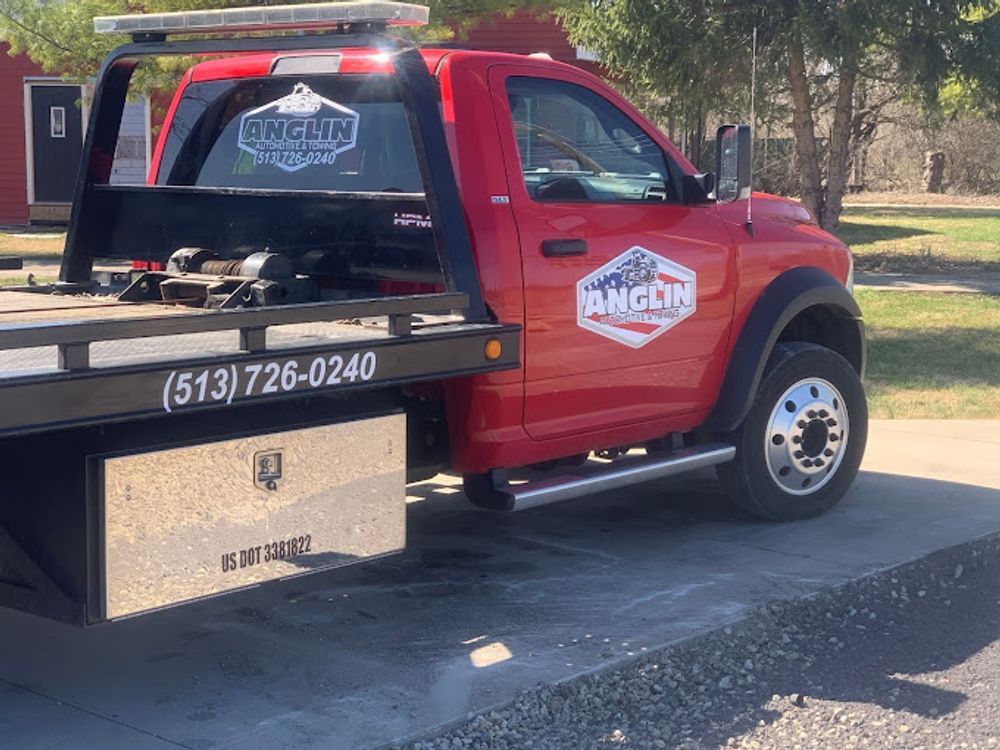 Red tow truck with company logo parked on a gray surface. Phone number visible.