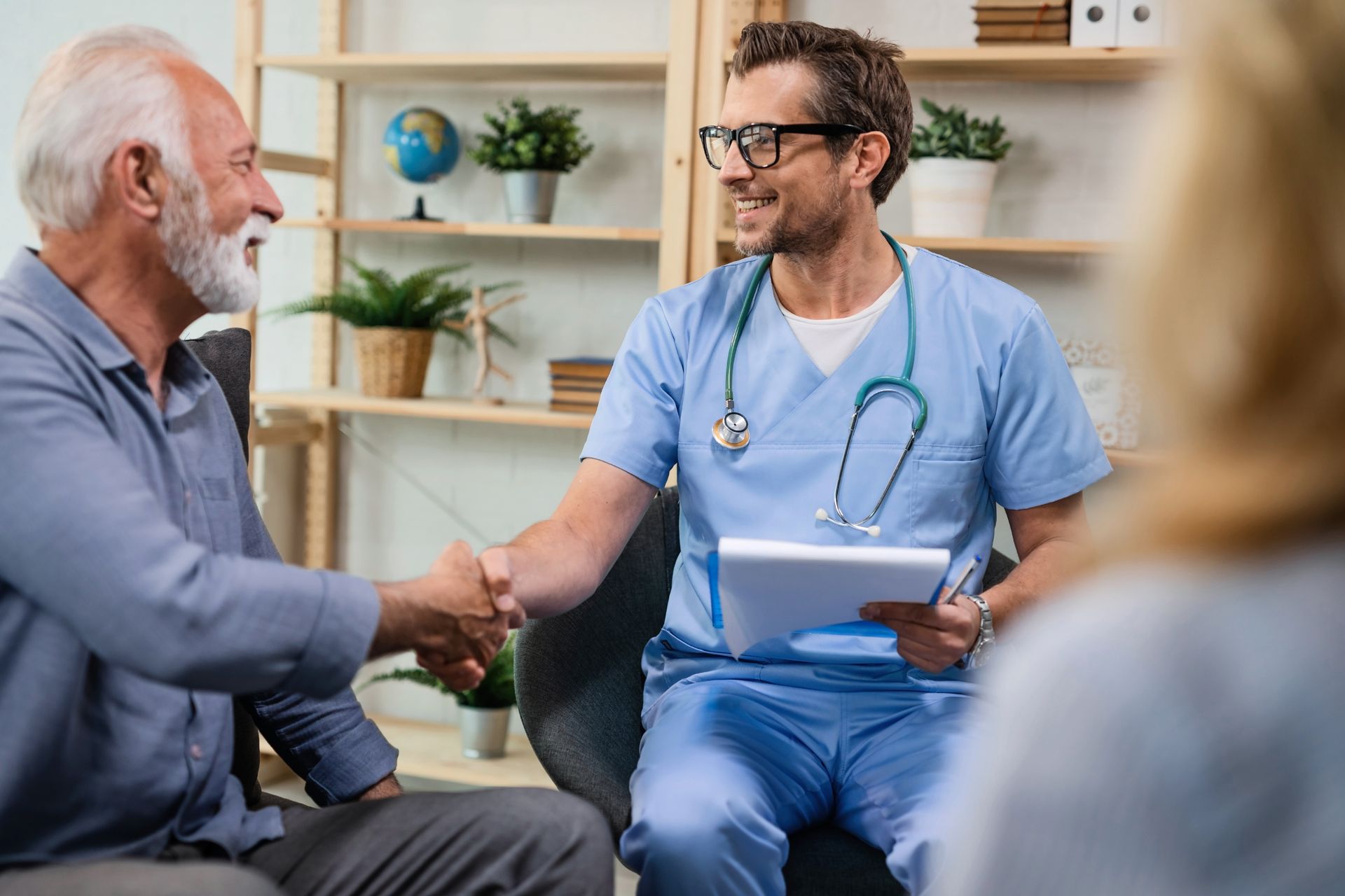 A doctor is shaking hands with an elderly man.