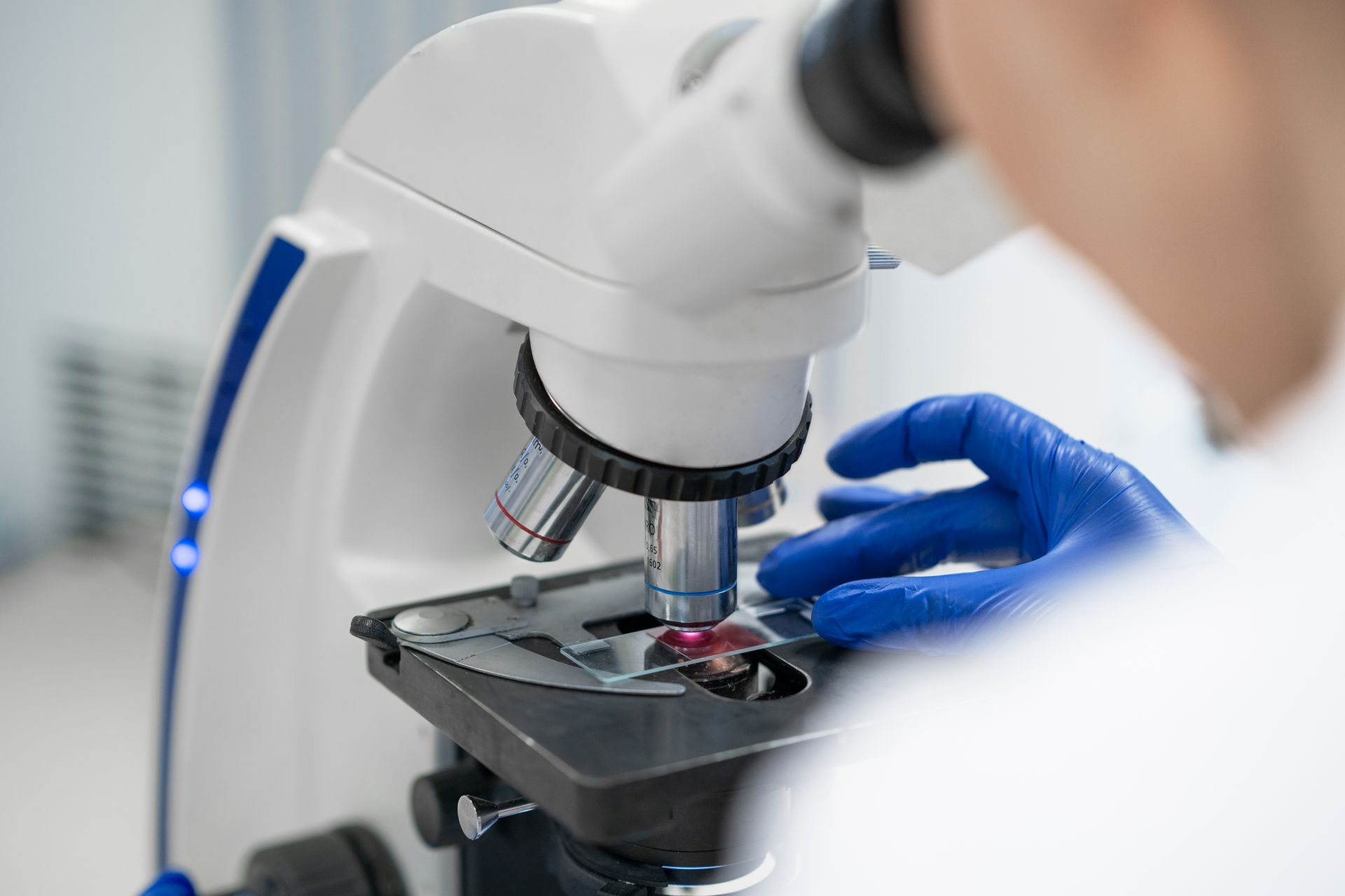 A person is looking through a microscope in a laboratory.