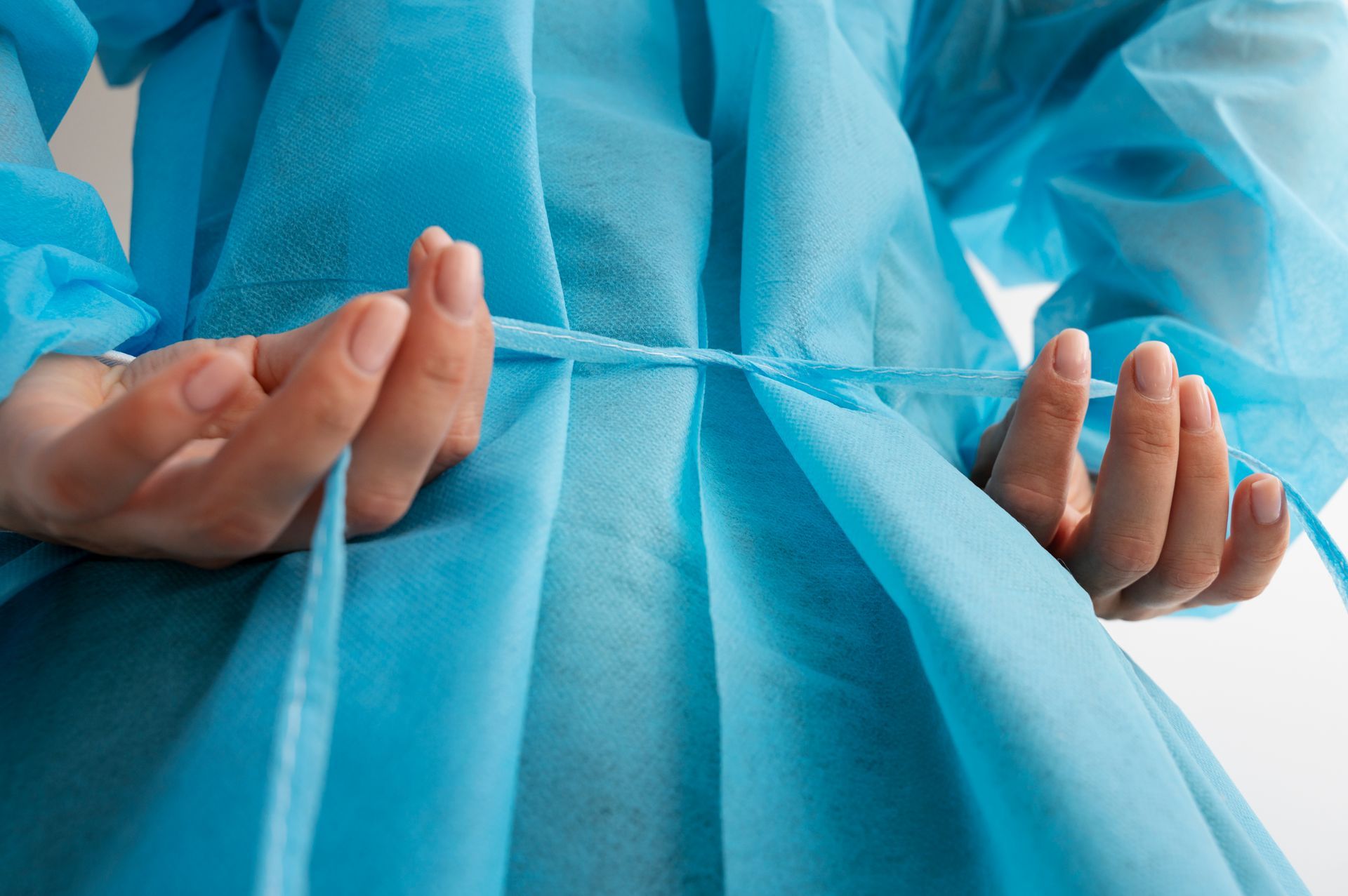 A person is tying a blue gown with a string.
