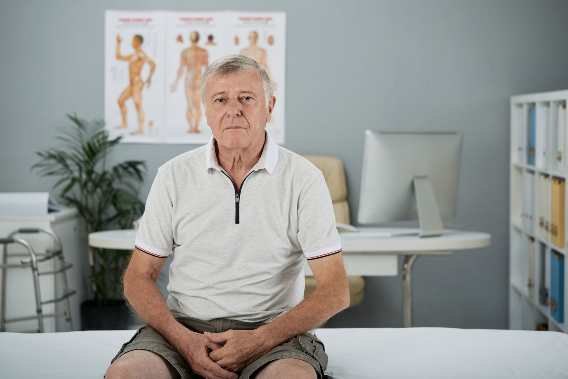 An elderly man is sitting on a bed in a doctor 's office.