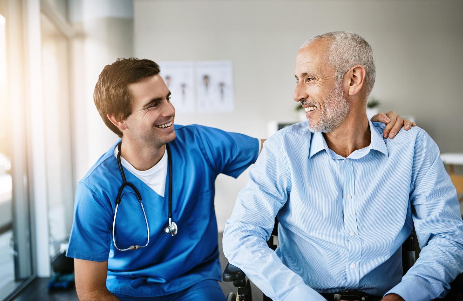 A nurse is talking to an older man in a wheelchair.