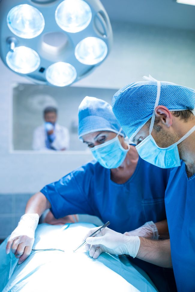 Two surgeons are working on a patient in an operating room