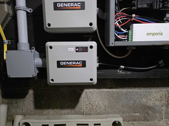 Generac generator control panel with Emporia energy monitor installed on a dark wall.