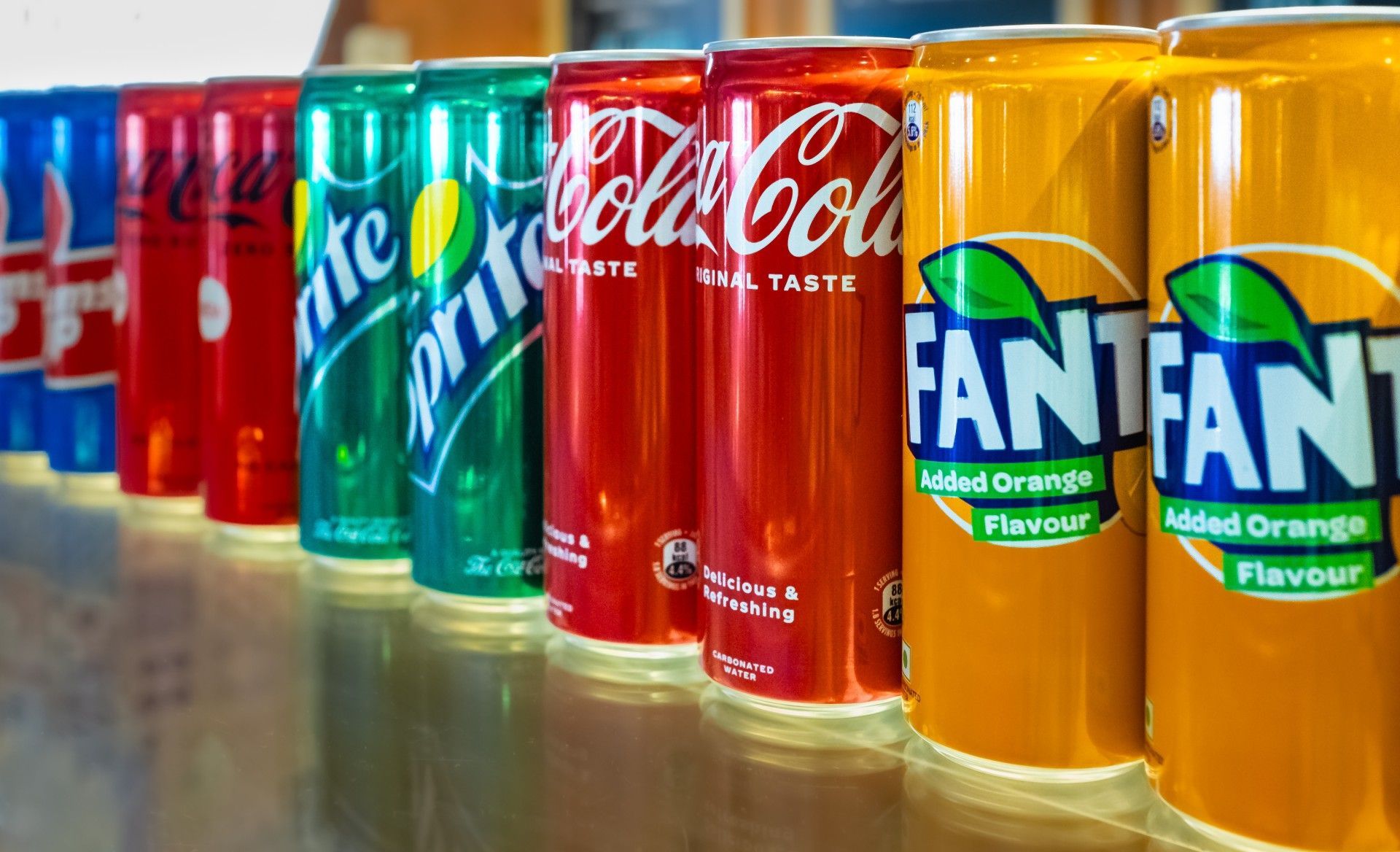 A row of cans of soda are lined up on a counter.