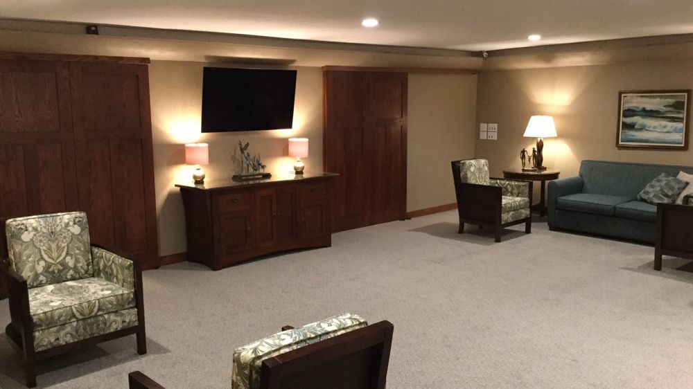 A living room with a couch , chairs , and a flat screen tv.