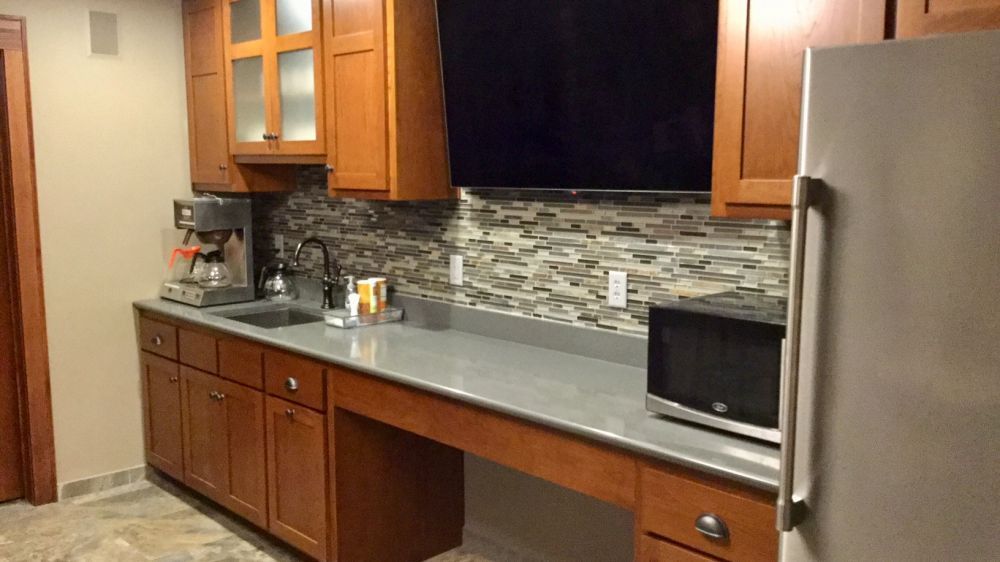 A kitchen with a refrigerator , microwave , sink and television.
