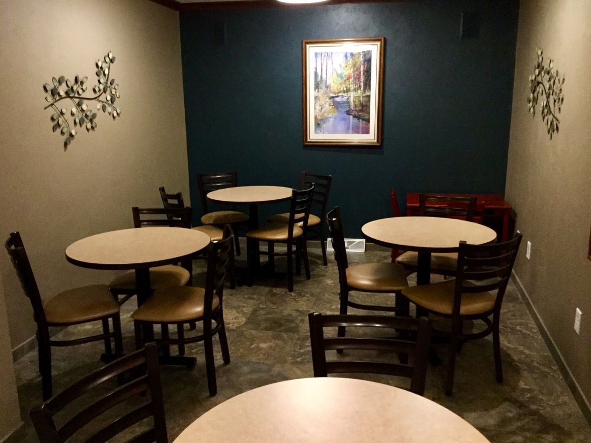 A room with tables and chairs and a picture on the wall.