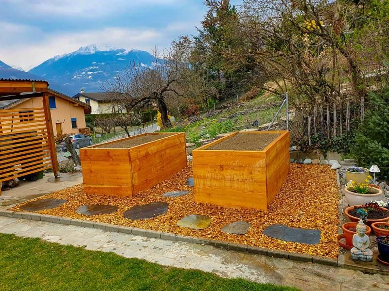 Deux plates-bandes surélevées en bois dans un jardin avec des montagnes en arrière-plan.