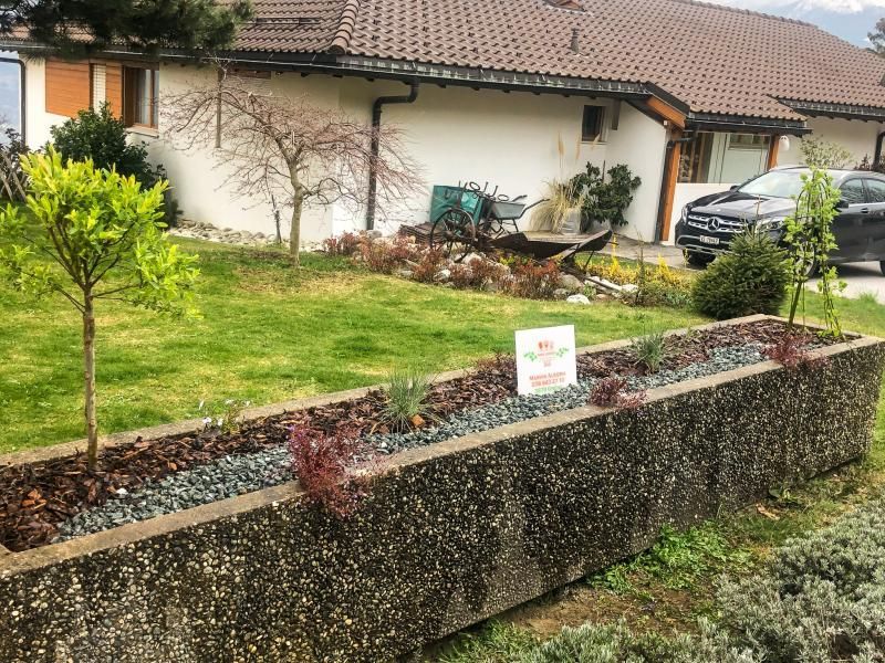 Une maison avec une jardinière en béton devant.