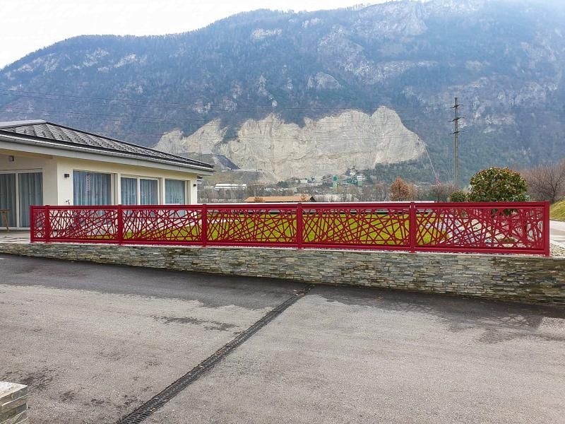 Une clôture rouge entoure une maison avec des montagnes en arrière-plan.