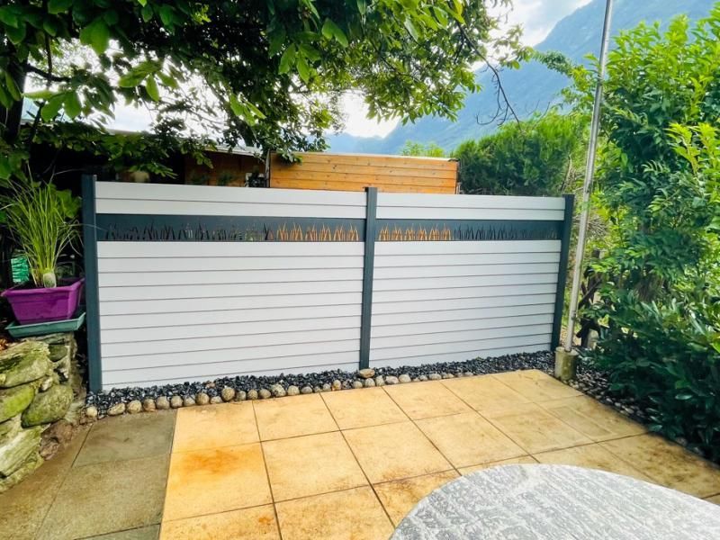 Une clôture blanche entoure un patio avec une table devant