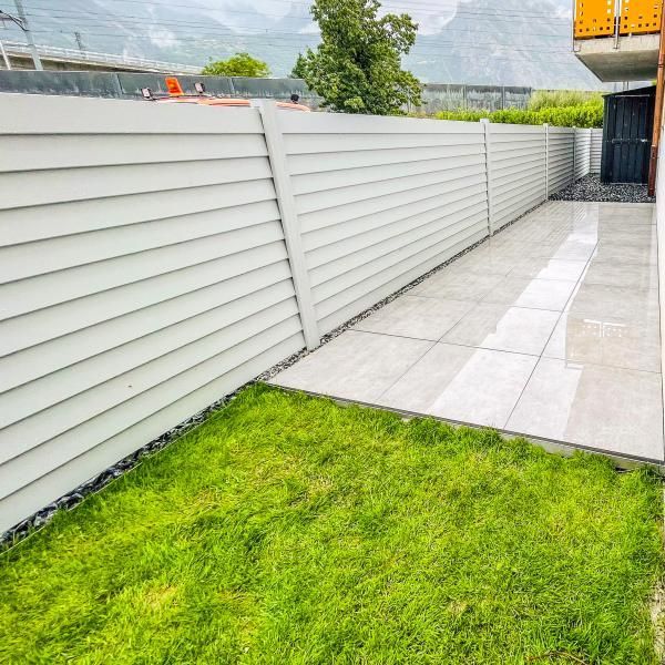 Une clôture blanche entoure une cour verdoyante.