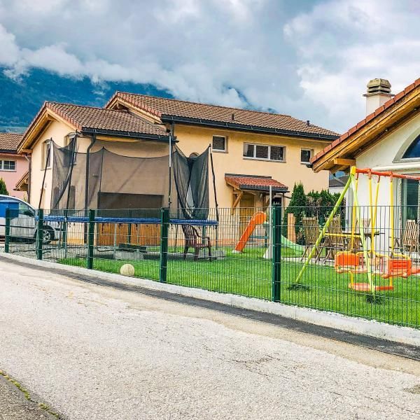 Une maison avec un trampoline et des balançoires devant