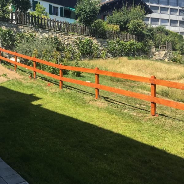 Une clôture en bois entoure un champ verdoyant