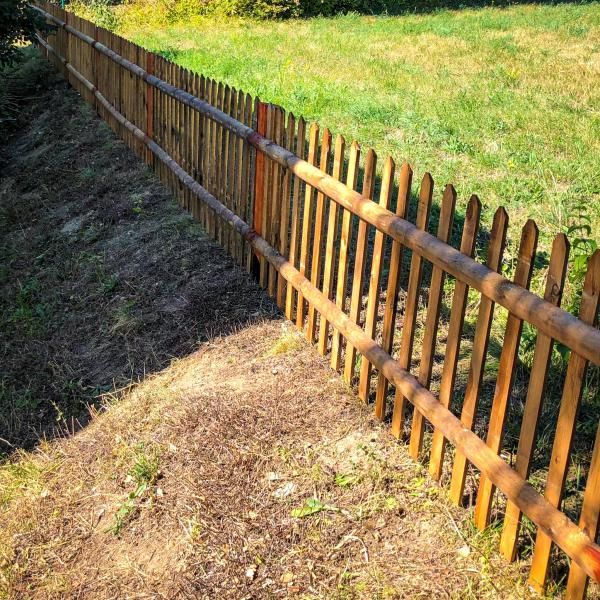 Une clôture en bois entoure un champ herbeux.