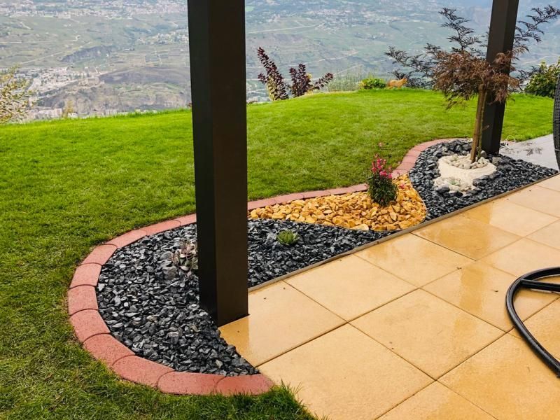 Un patio avec vue sur une colline herbeuse et un tuyau au premier plan.