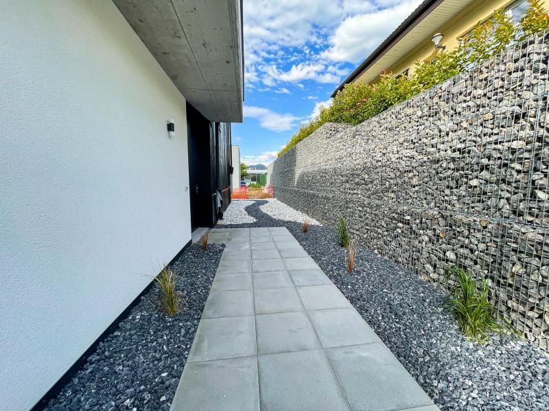 Une allée menant à une maison avec un mur de pierre en arrière-plan