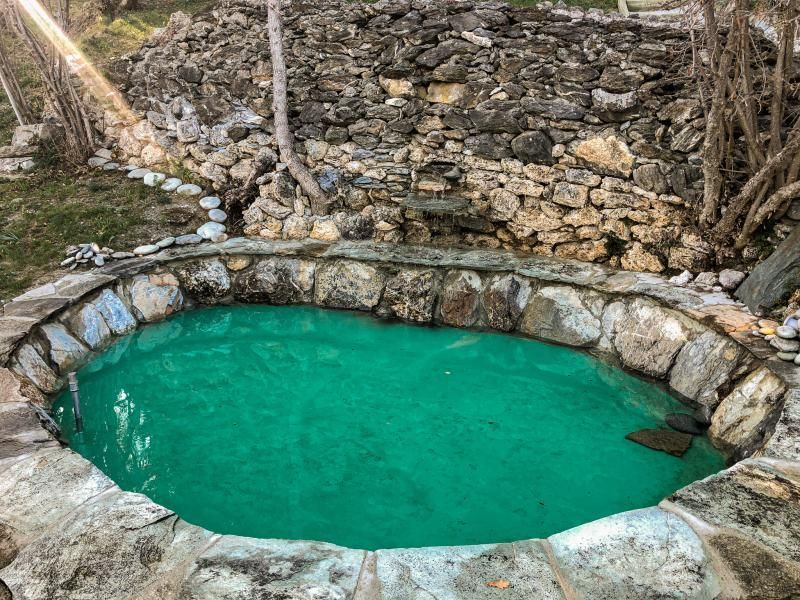 Une piscine en pierre remplie d'eau verte entourée de rochers.