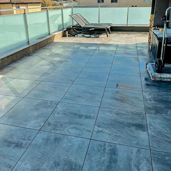 Un patio avec une balustrade en verre et des chaises dessus.