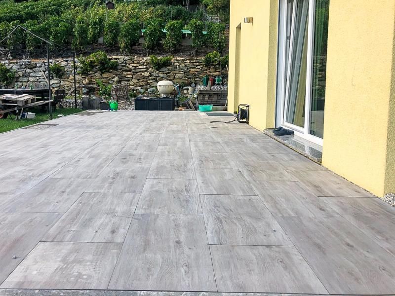 Un patio avec un plancher en bois et un bâtiment jaune en arrière-plan.