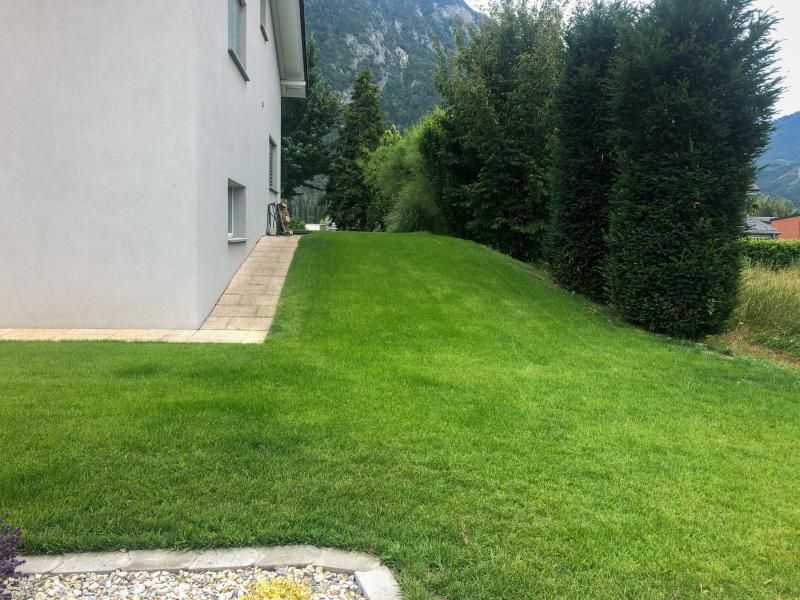 Une grande pelouse devant une maison avec une rampe qui y mène.