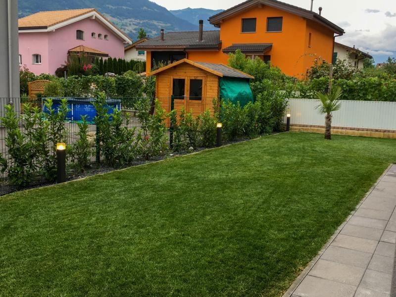 Une pelouse verte luxuriante devant une maison orange