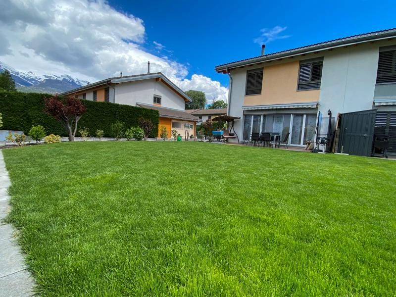 Une grande pelouse verte luxuriante devant une maison.