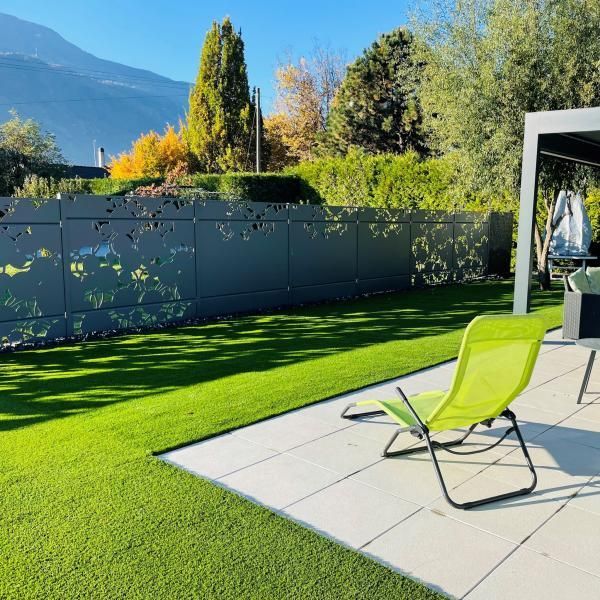 Une chaise verte est posée sur une terrasse à côté d'une clôture