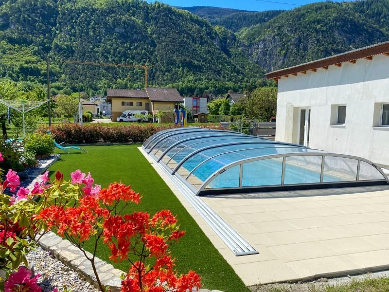 Une piscine avec une couverture transparente et des montagnes en arrière-plan