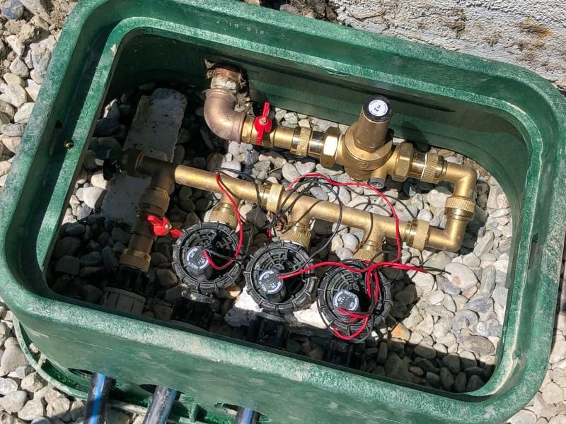 Une boîte verte remplie de tuyaux et de fils en laiton.