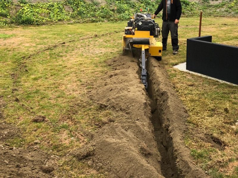 Un homme se tient à côté d'une machine qui creuse un trou dans le sol.