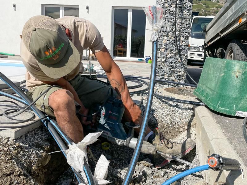 Un homme portant un chapeau travaille sur un tuyau dans la terre.