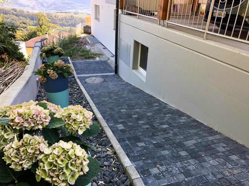 Une allée avec des fleurs sur le côté à côté d'un bâtiment.