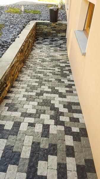 Une passerelle en briques noires et blanches à côté d'un bâtiment.
