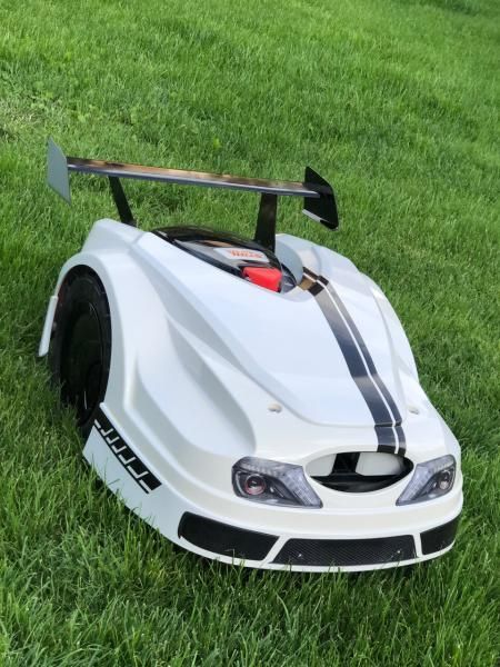 Une tondeuse à gazon qui ressemble à une voiture de course est assise dans l'herbe.