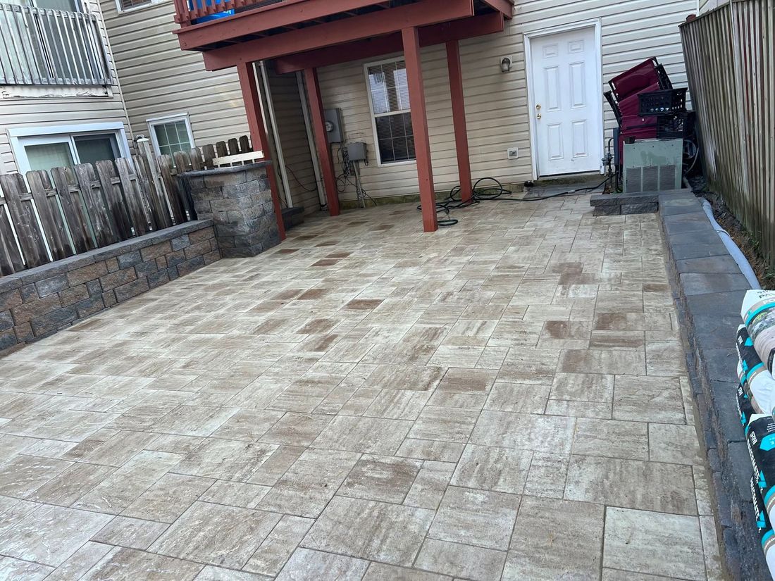 Empty stone patio beside a brick house with a covered awning and side gate