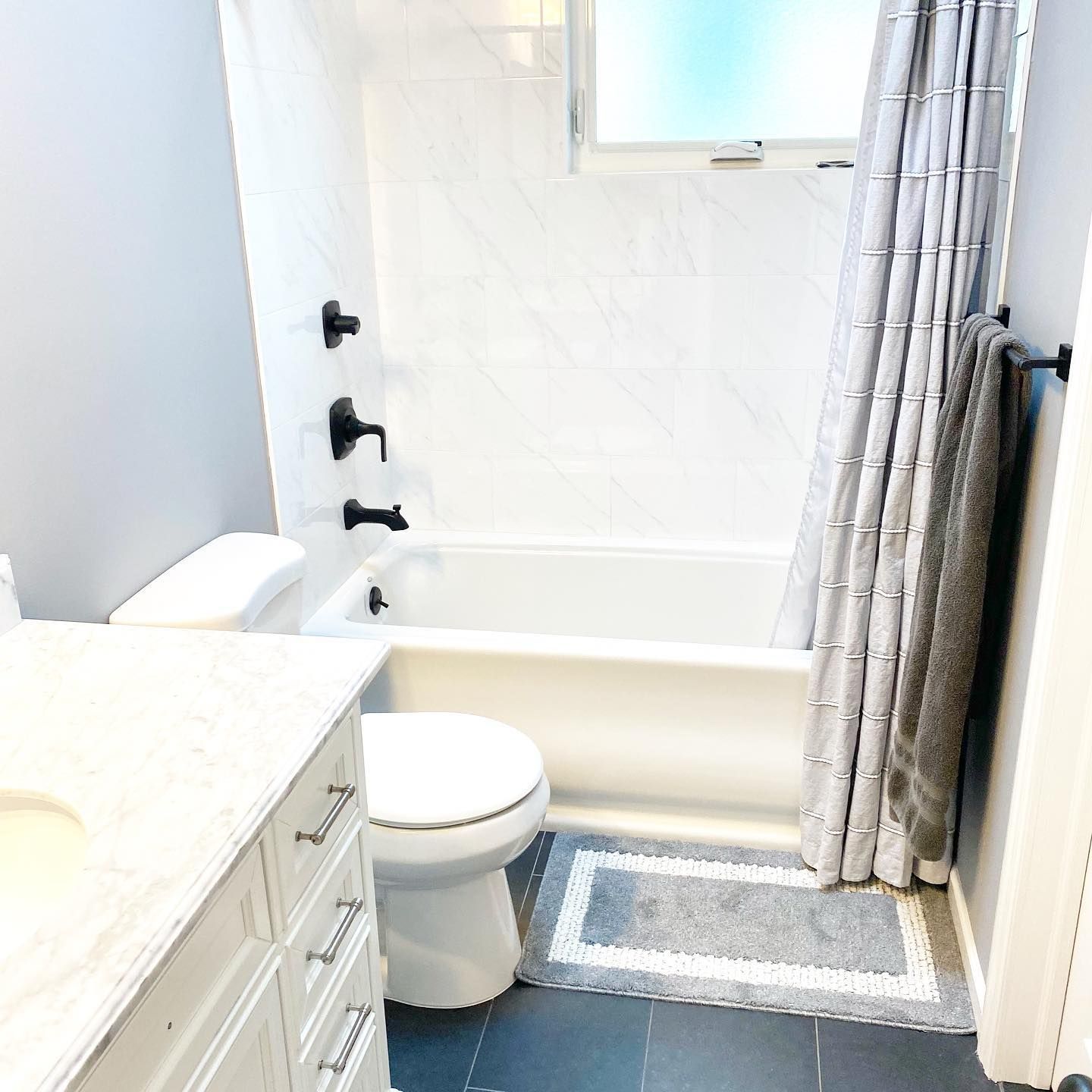 A bathroom with a toilet a tub and a window