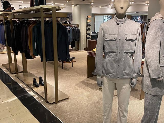 A mannequin wearing a grey jacket and white pants in a store