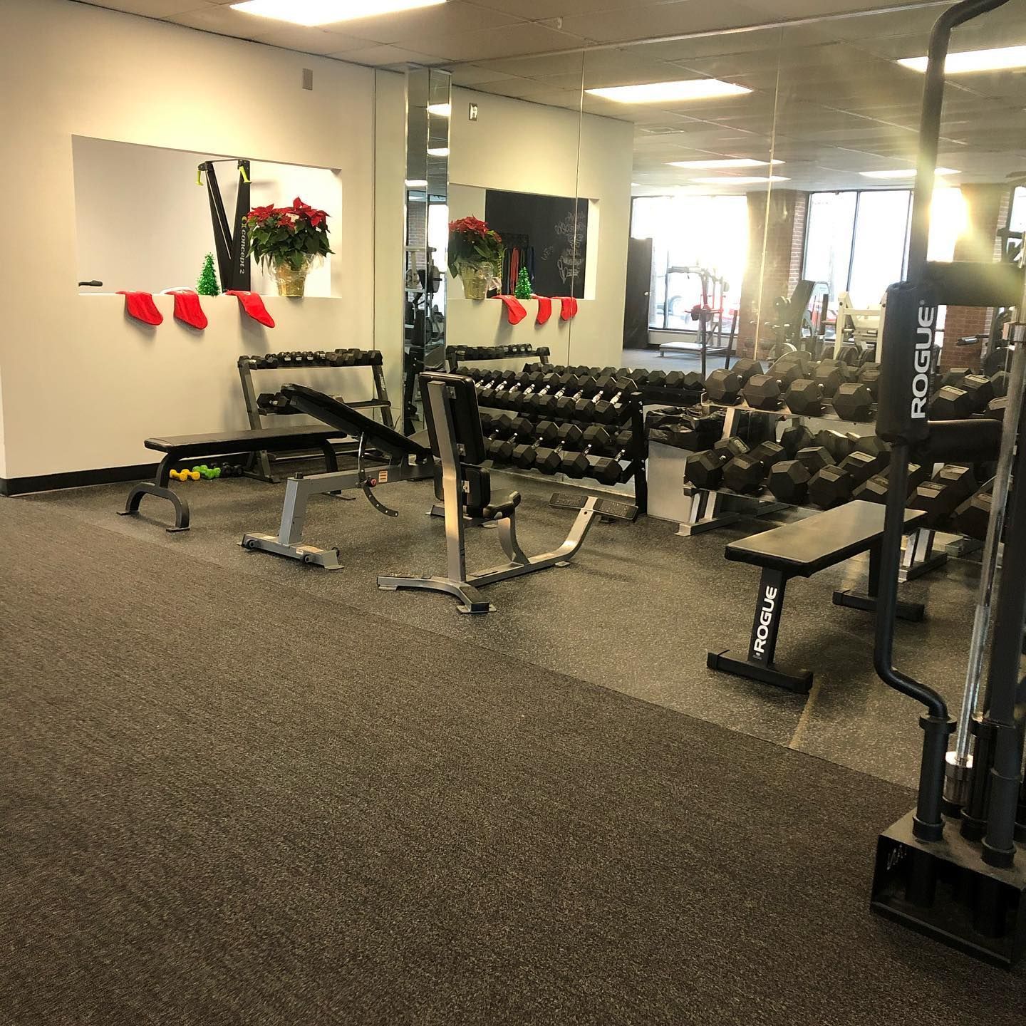 A gym with a lot of dumbbells and a machine that says rogue