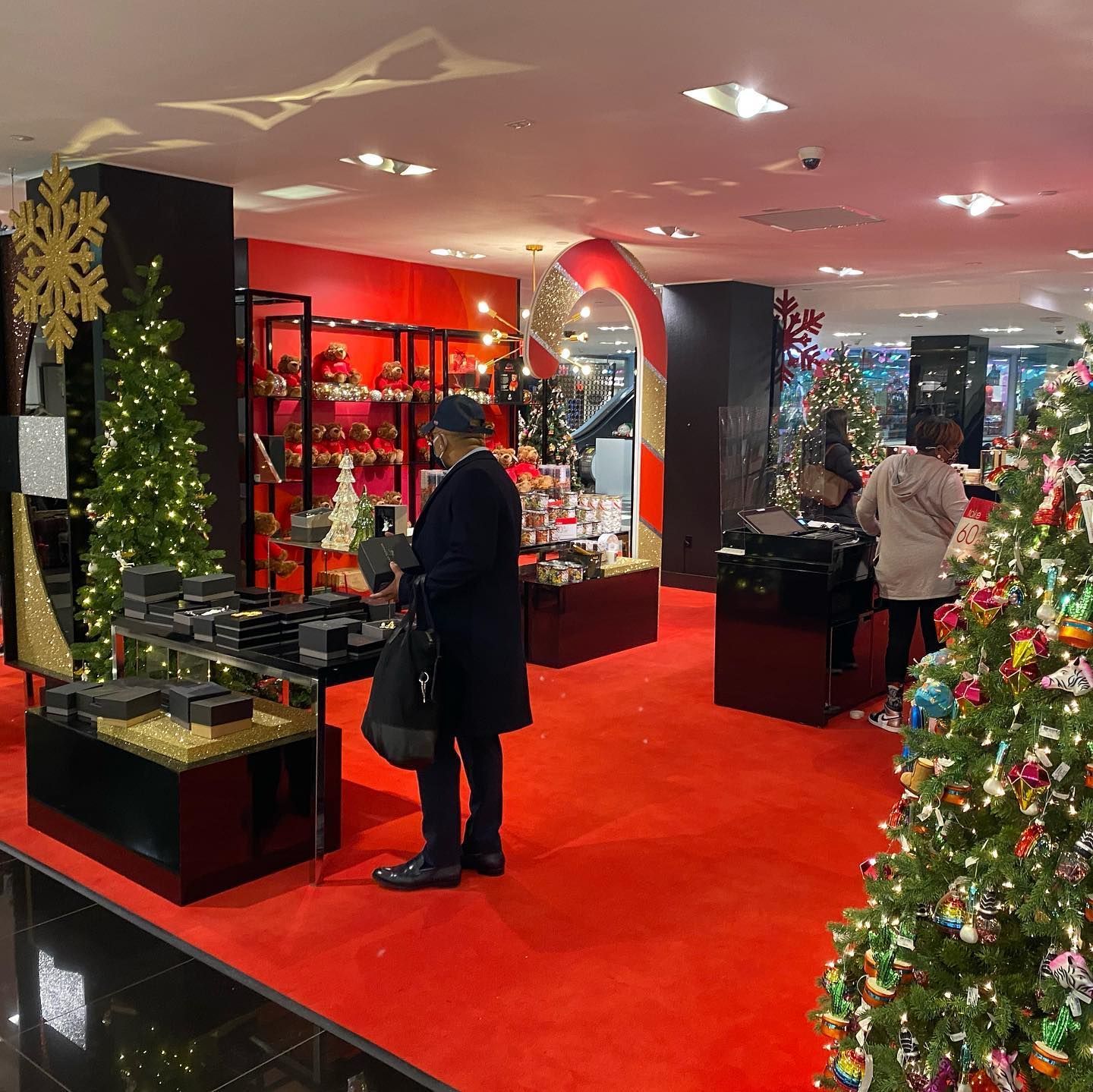A man is standing in a store surrounded by christmas trees