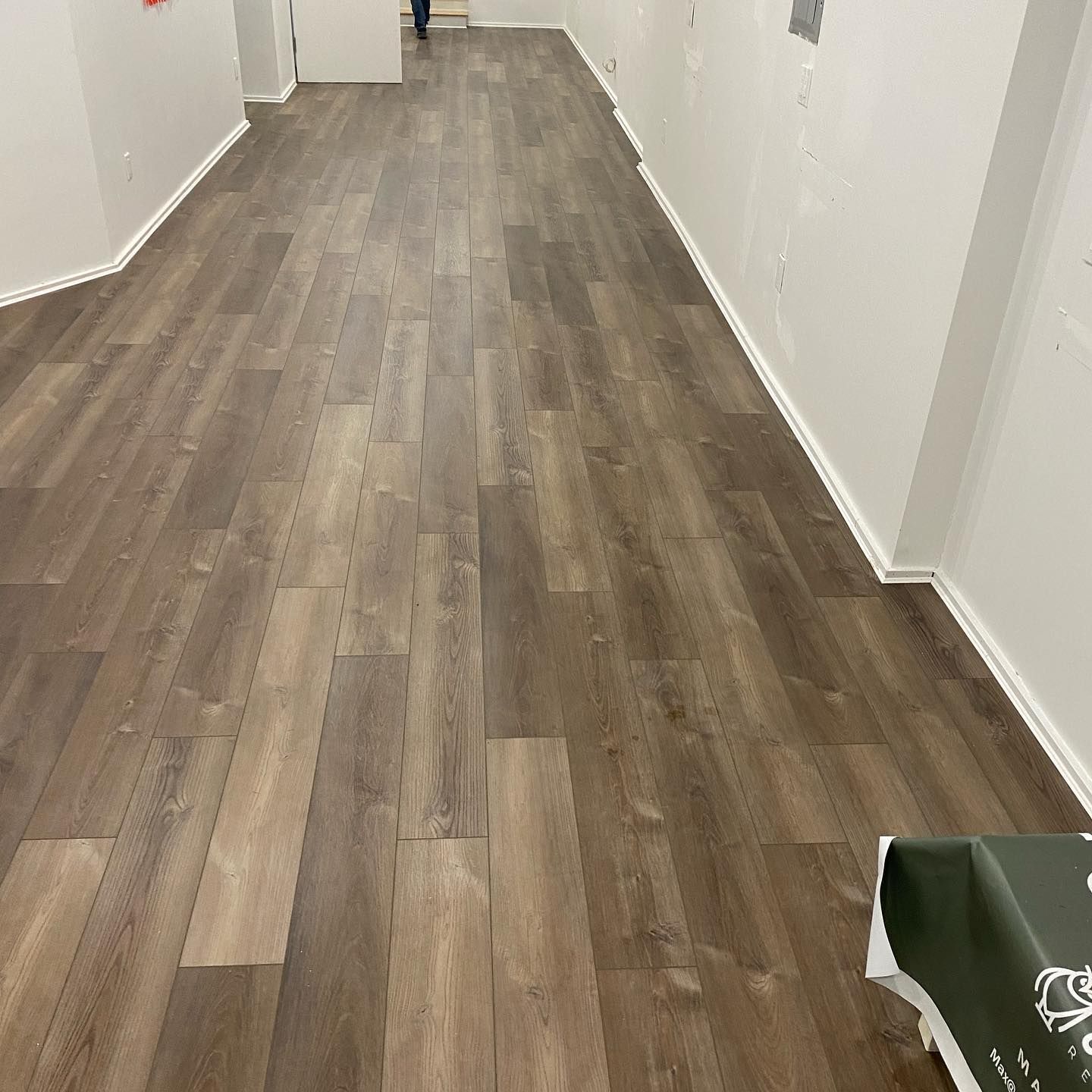 A long hallway with a wooden floor and white walls.